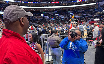 A woman photographing a man at a basketball game.