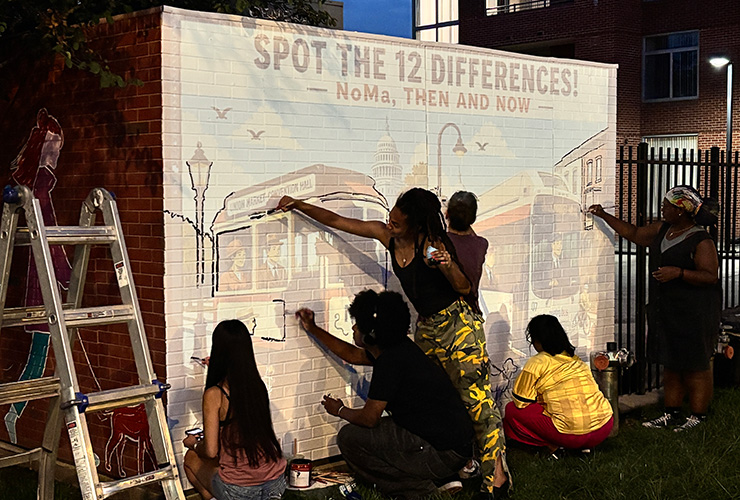 Mural being painted at night over a projection.