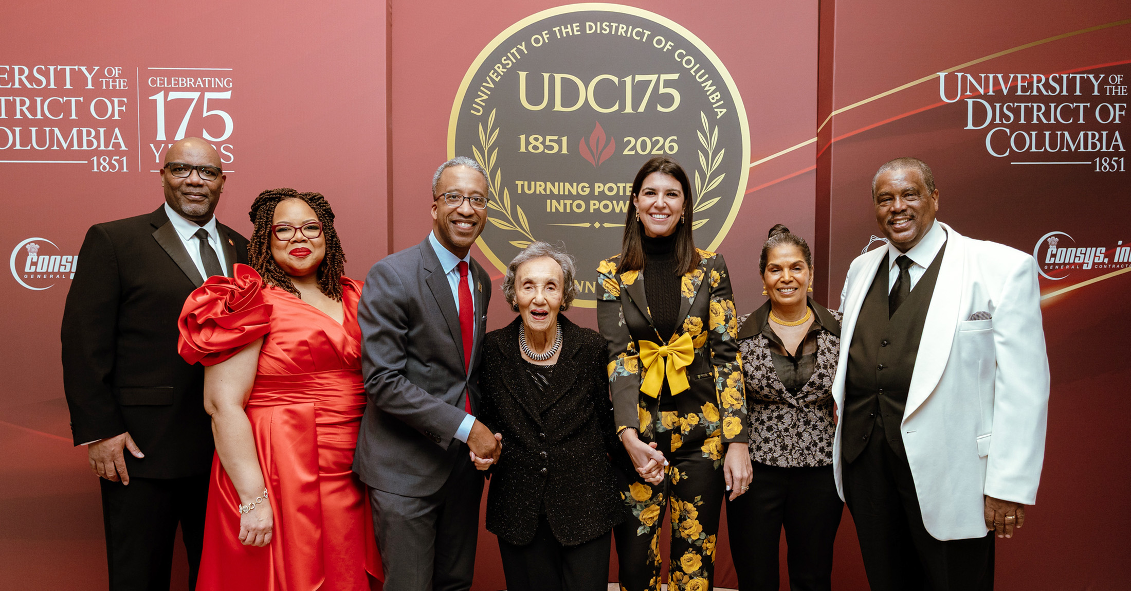 A group of people wearing formal attire and smiling.