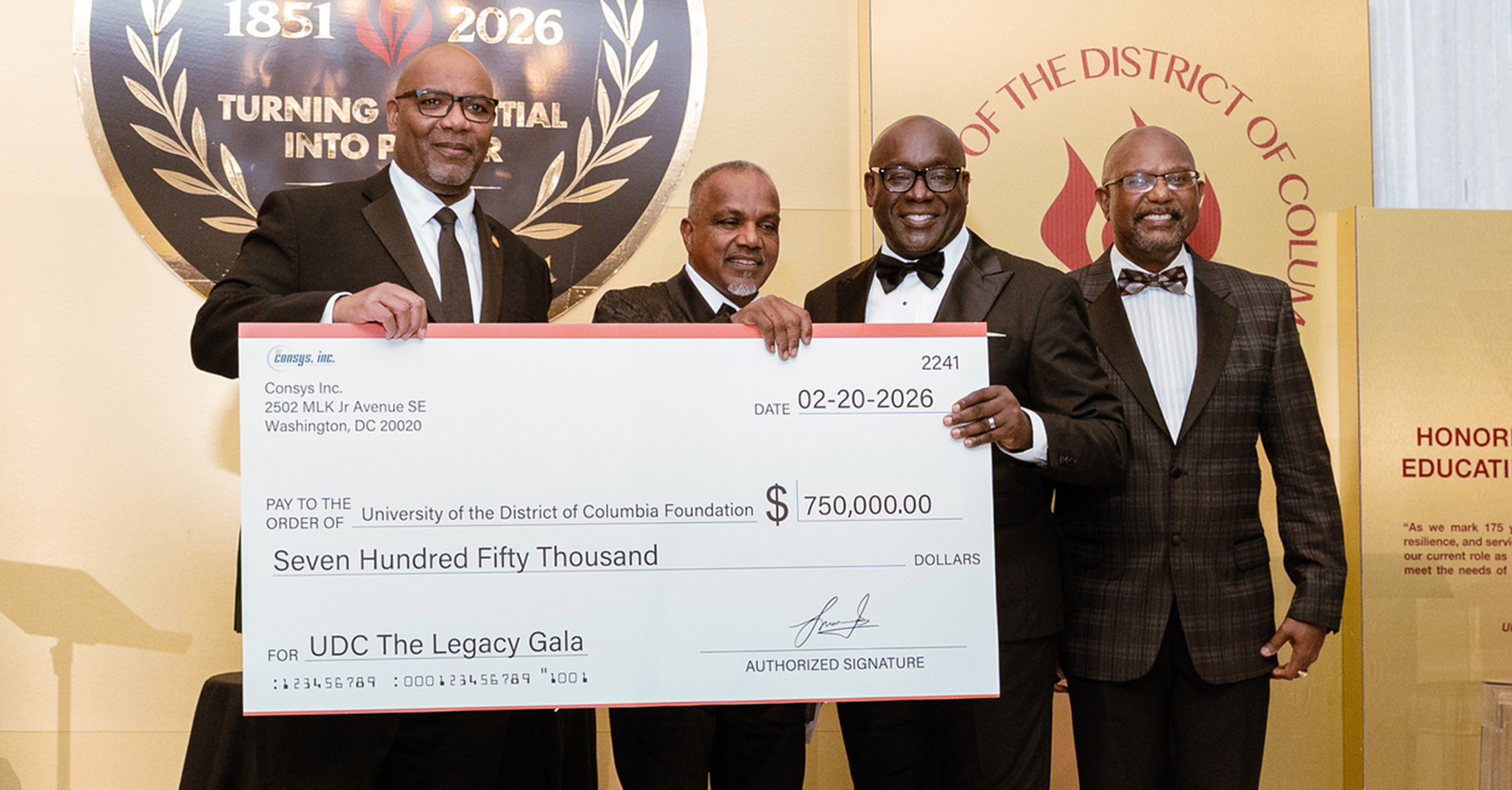 Four men in tuxedos holding an over-sized check for $750,000