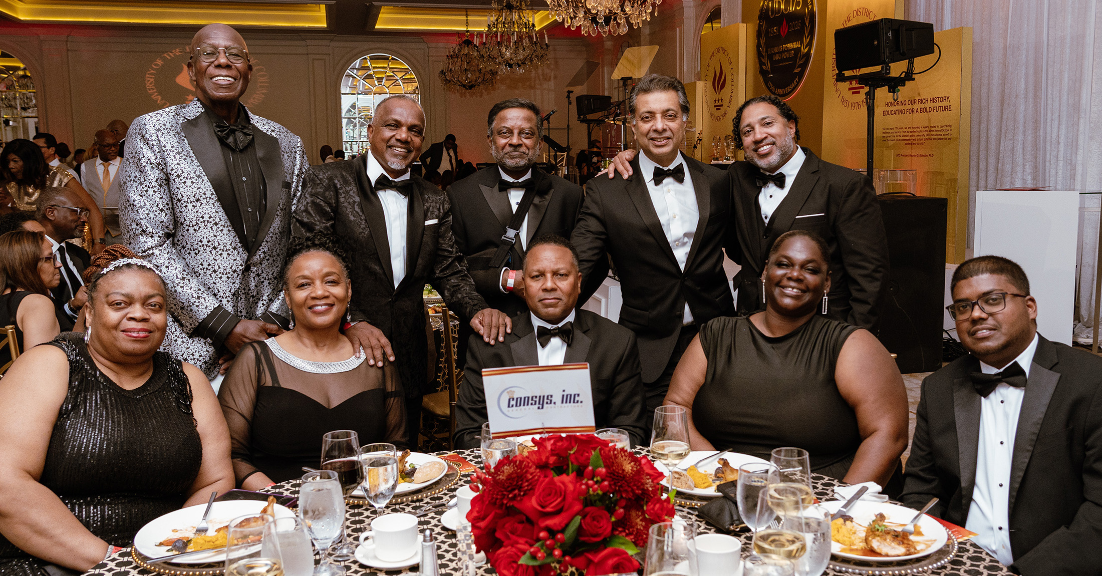 Several people wearing formal attire sitting around a table at a gala.