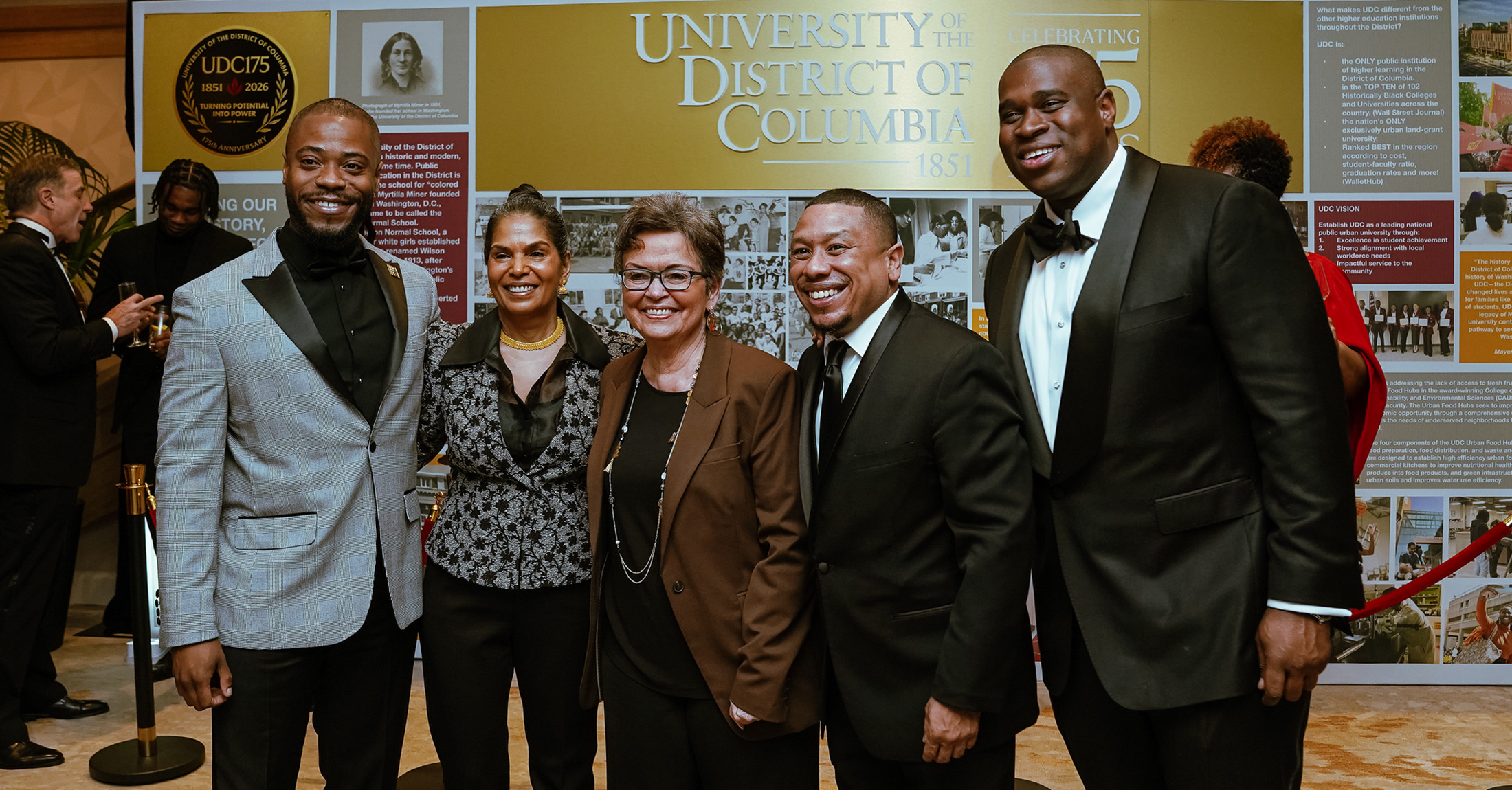 A group of people wearing formal attire standing and smiling.