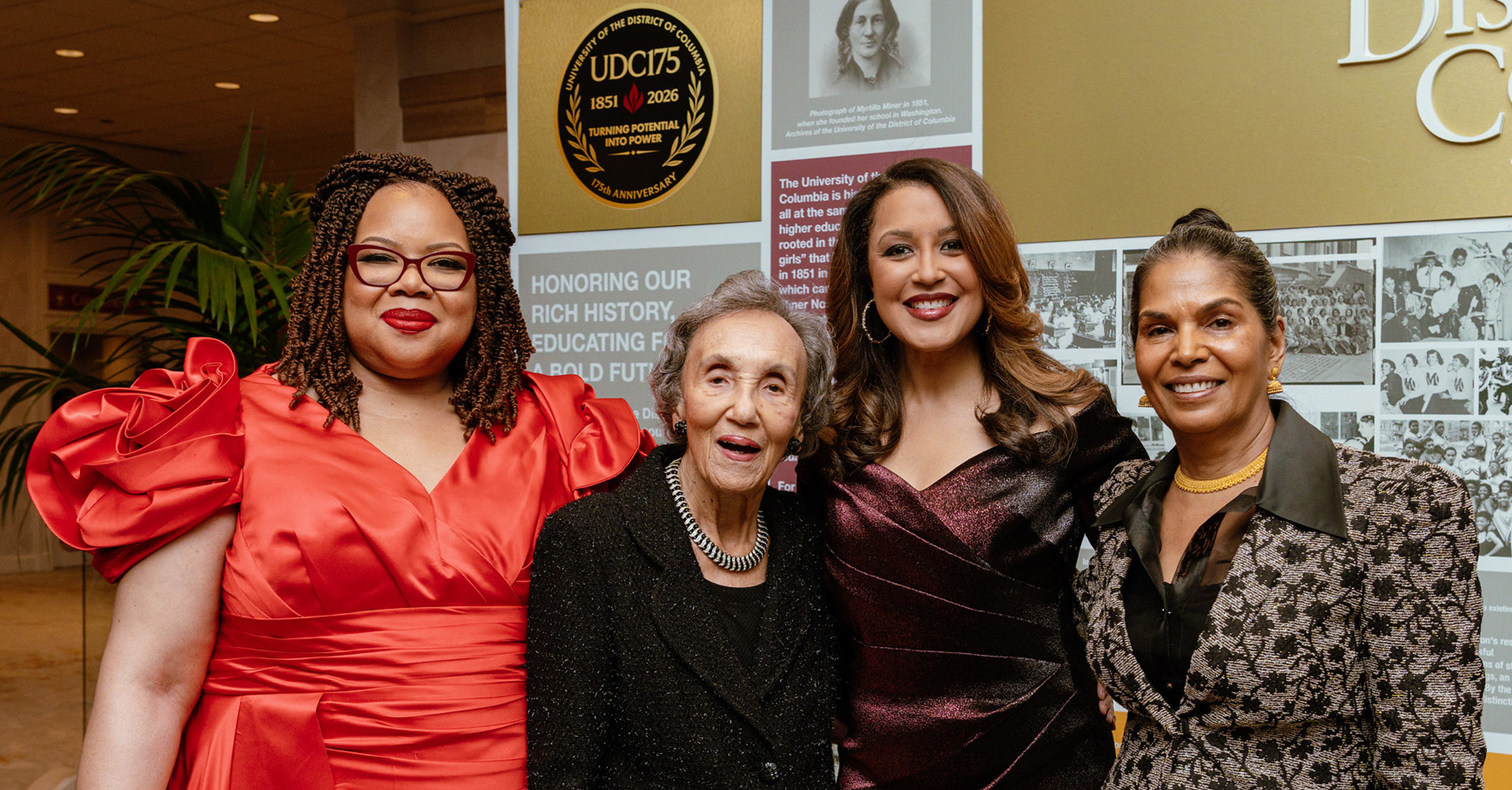 A group of women wearing formal attire standing and smiling.