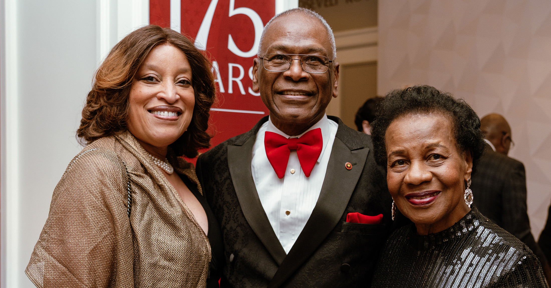 A group of people wearing formal attire standing and smiling.
