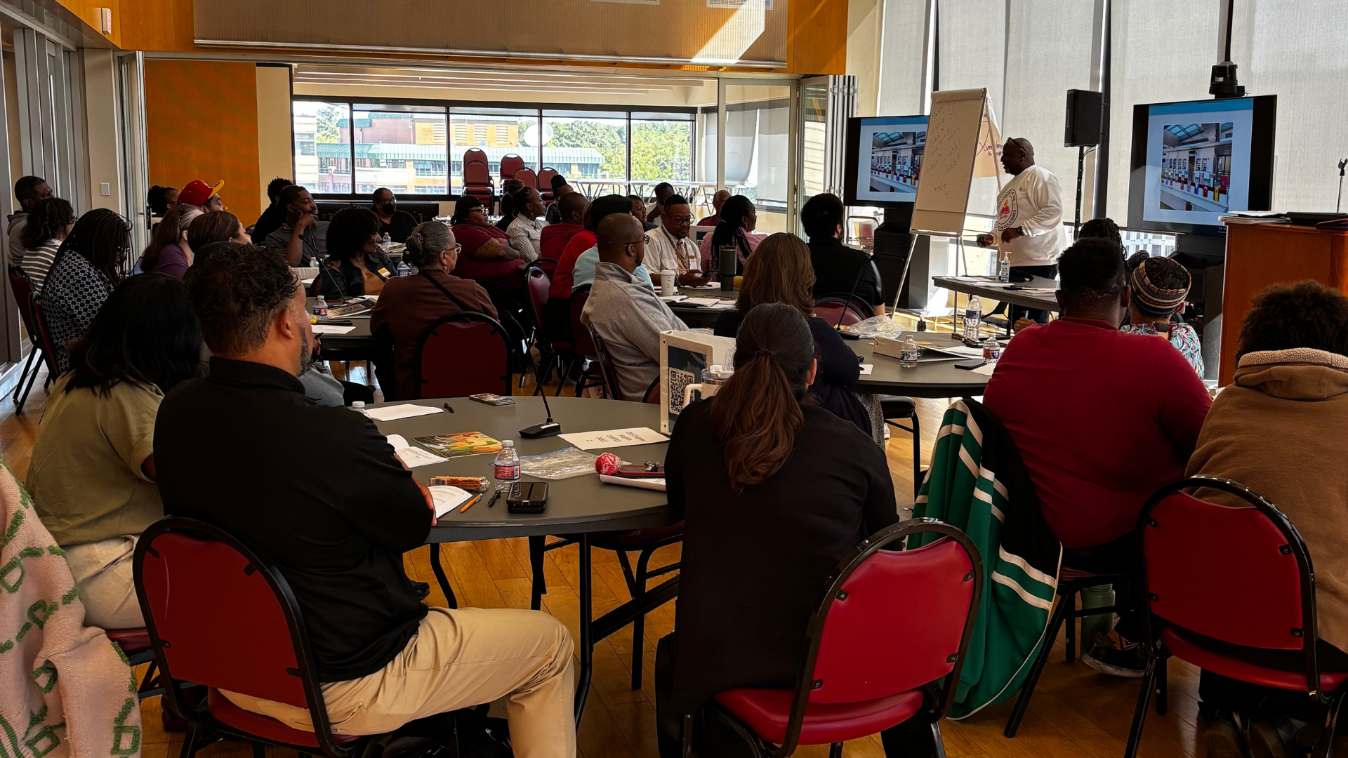 Trainer speaking to a room of employees sitting at tables