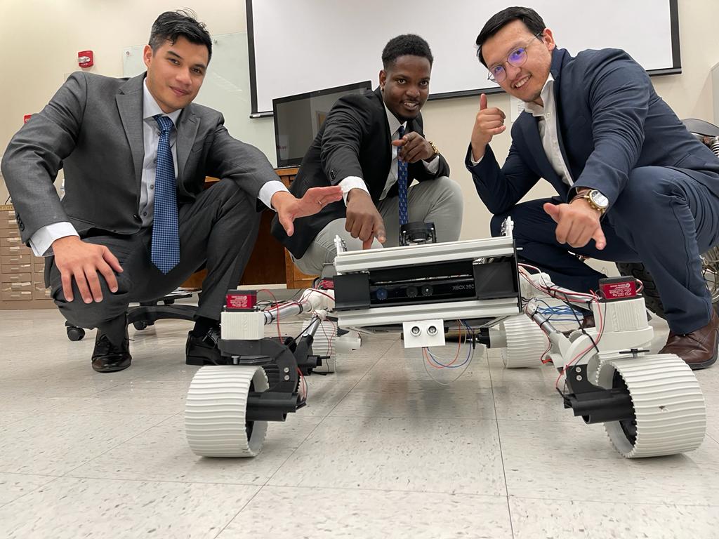 Three college students pose with their robots.