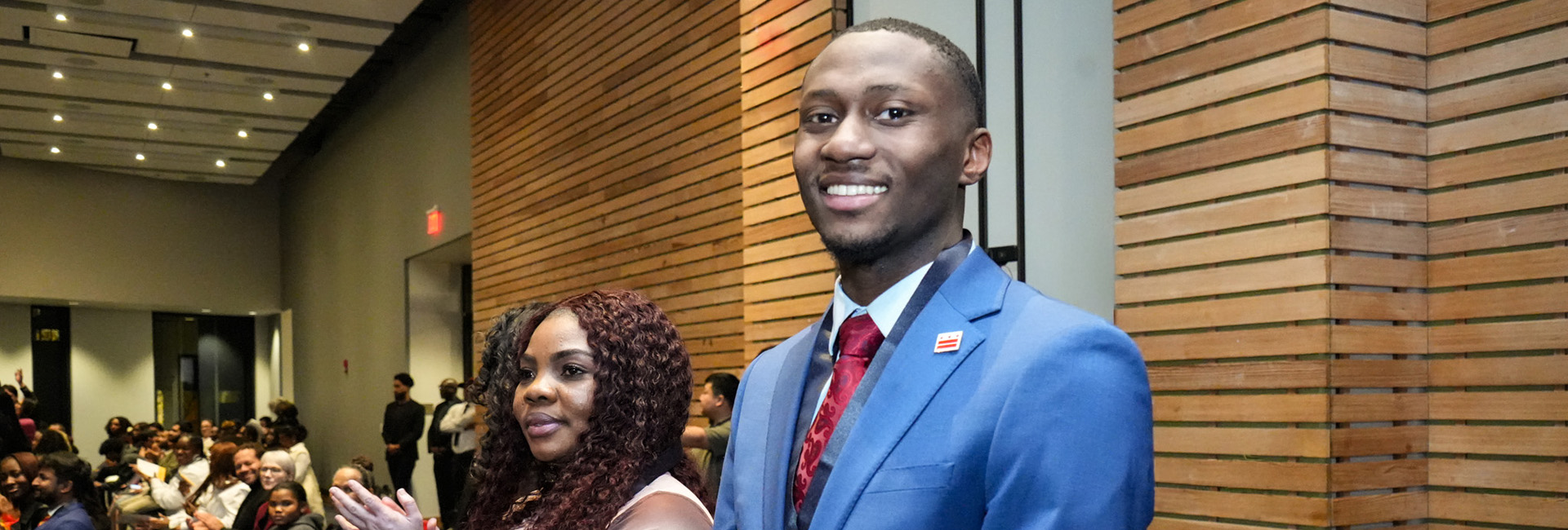 Three smiling college students in front of UDC's student center