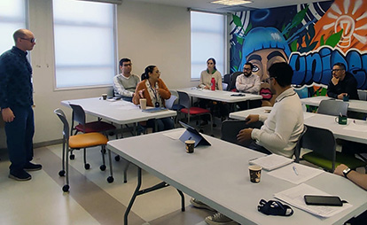 Brandon Schweitzer in front of a group of adult students in a classroom.