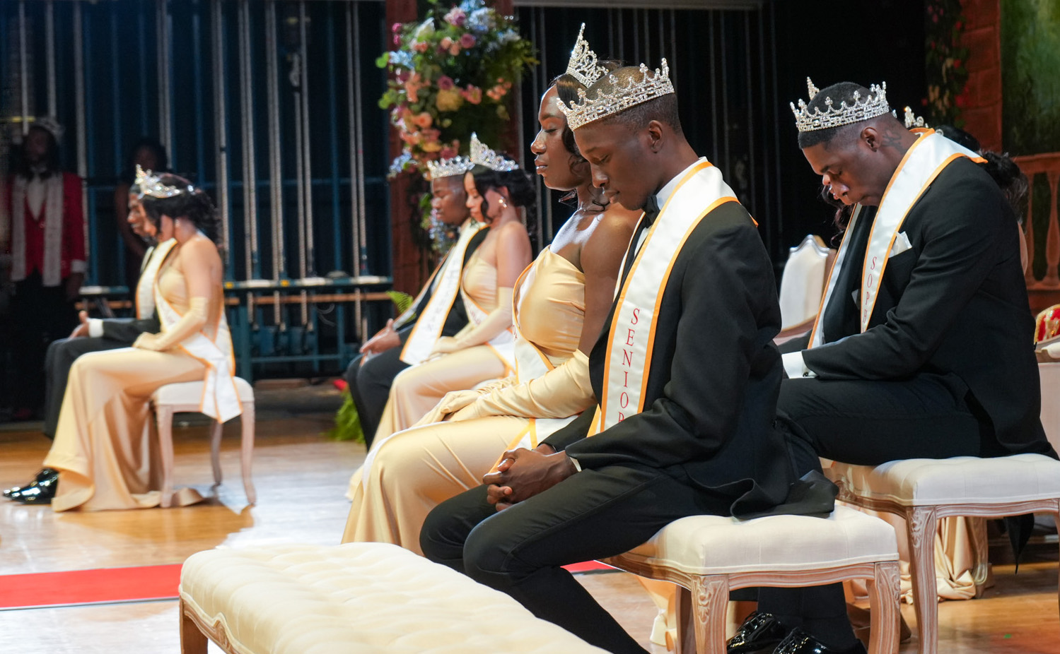 Members of the UDC Royal Court bow their heads in prayer during coronation.