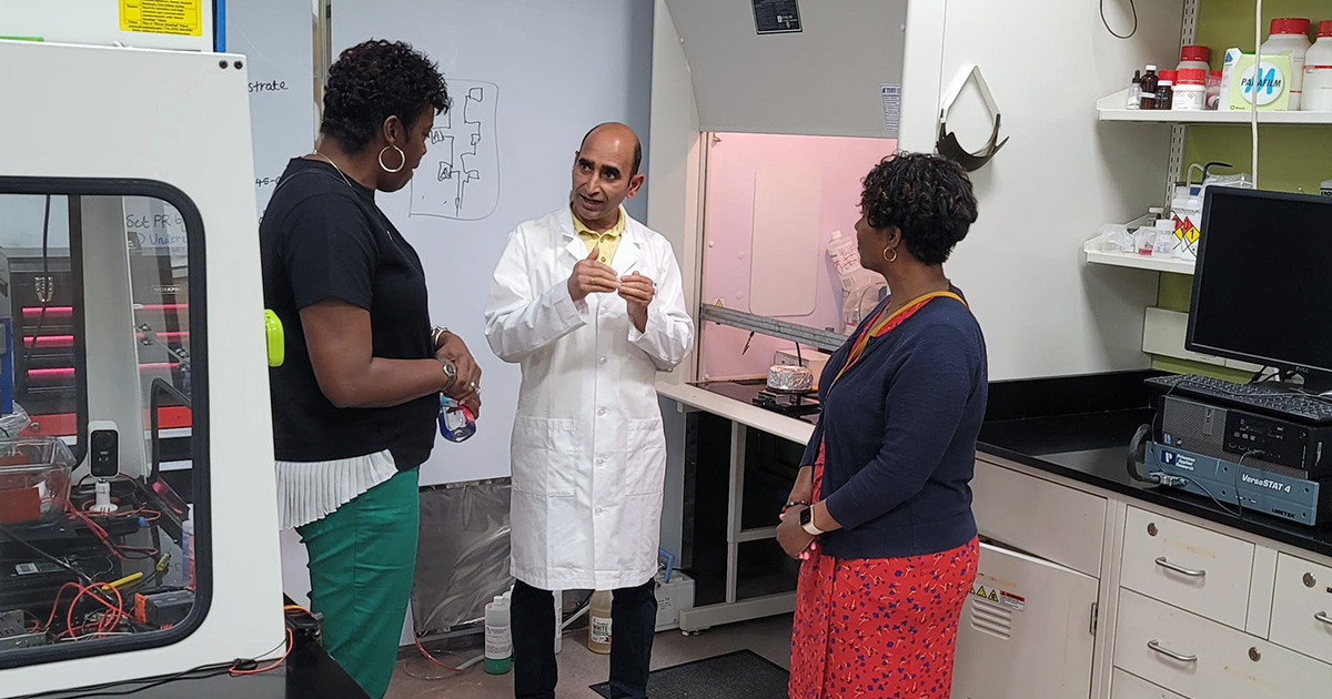 Pawan Tyagi in a lab talking with two women.