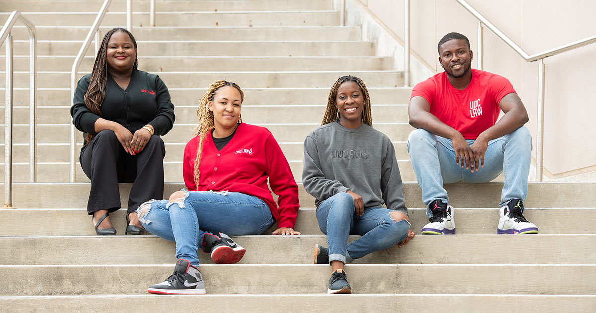 Four UDC law students sitting on steps at the Van Ness Campus
