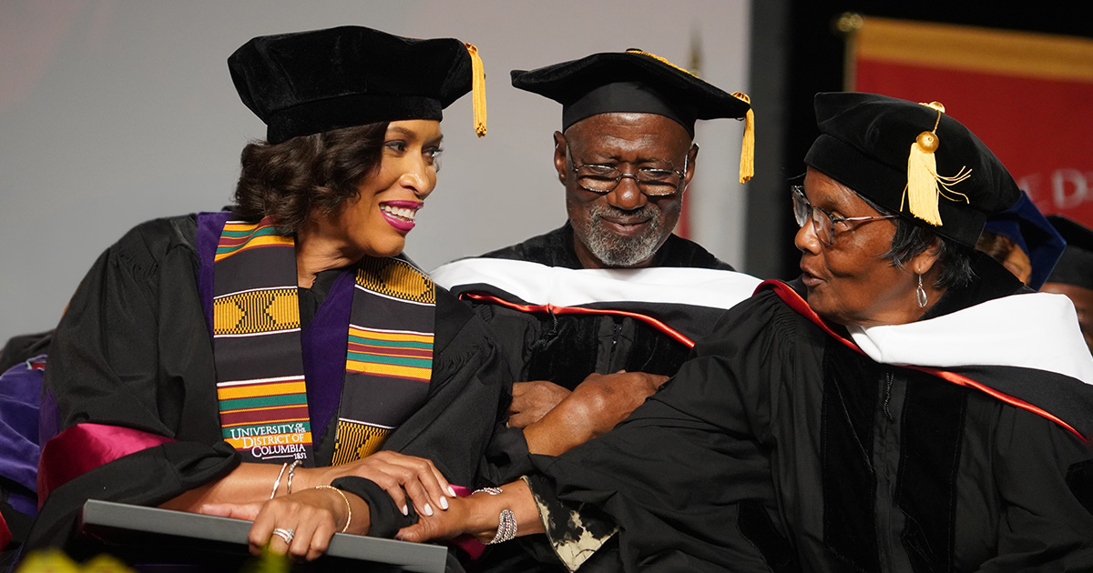 Mayor Muriel Bowser talking and smiling with Dennis and Zandra Chestnut during 2026 Commencement Ceremony.