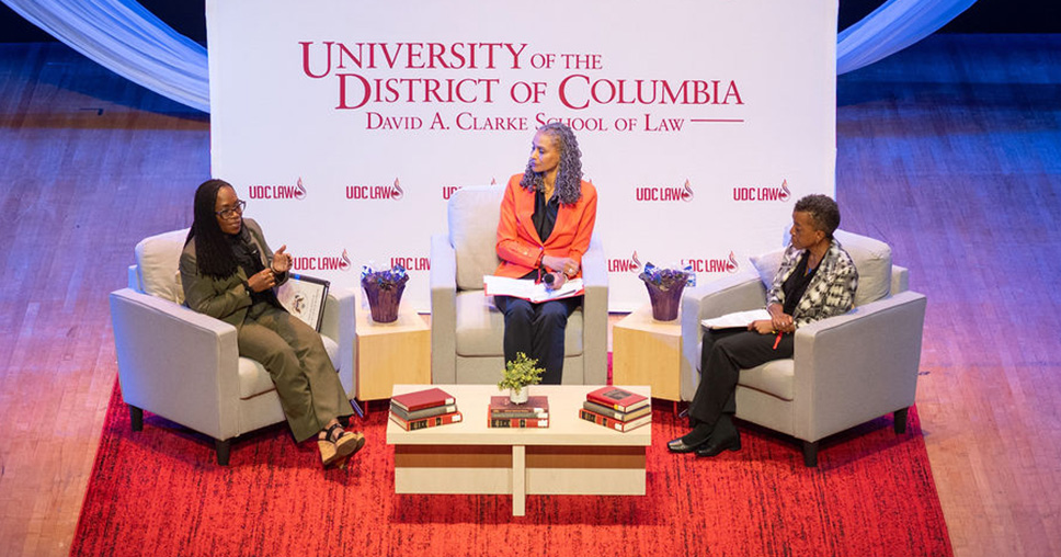 three women on a stage sitting town hall style