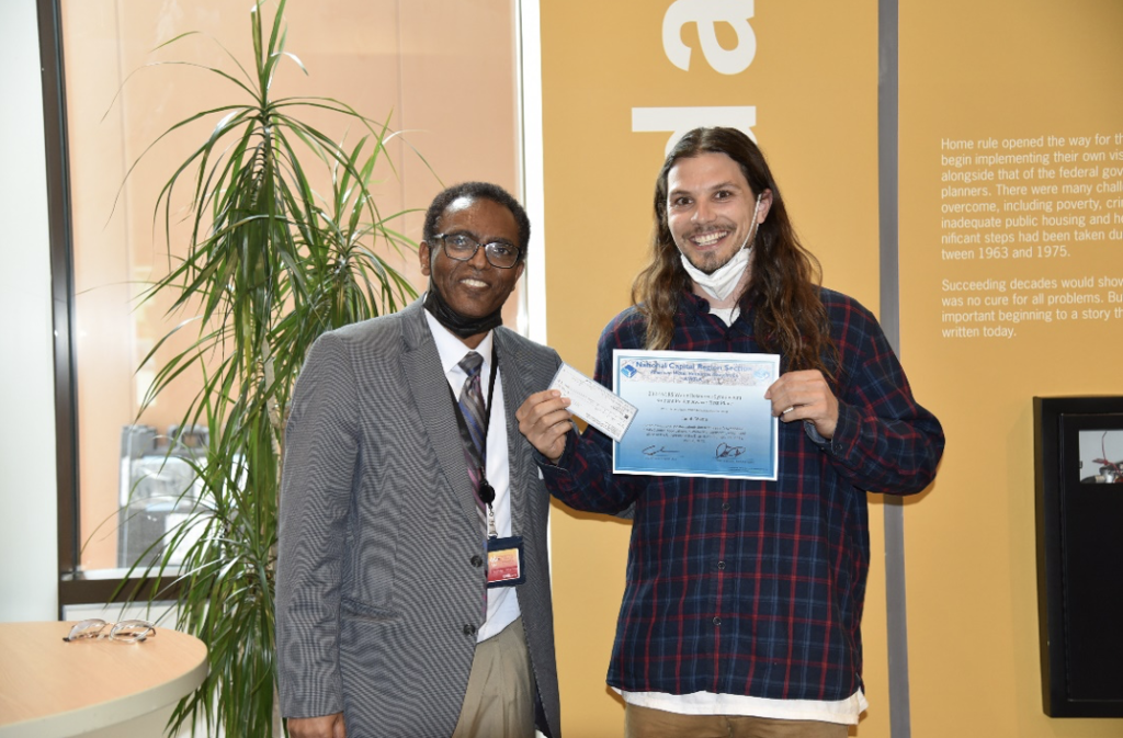 Professor Tolessa Deksissa, president of NCR-AWRA and director of WRRI, presenting the first-prize poster award to UDC graduate student, Jacob Wynn.